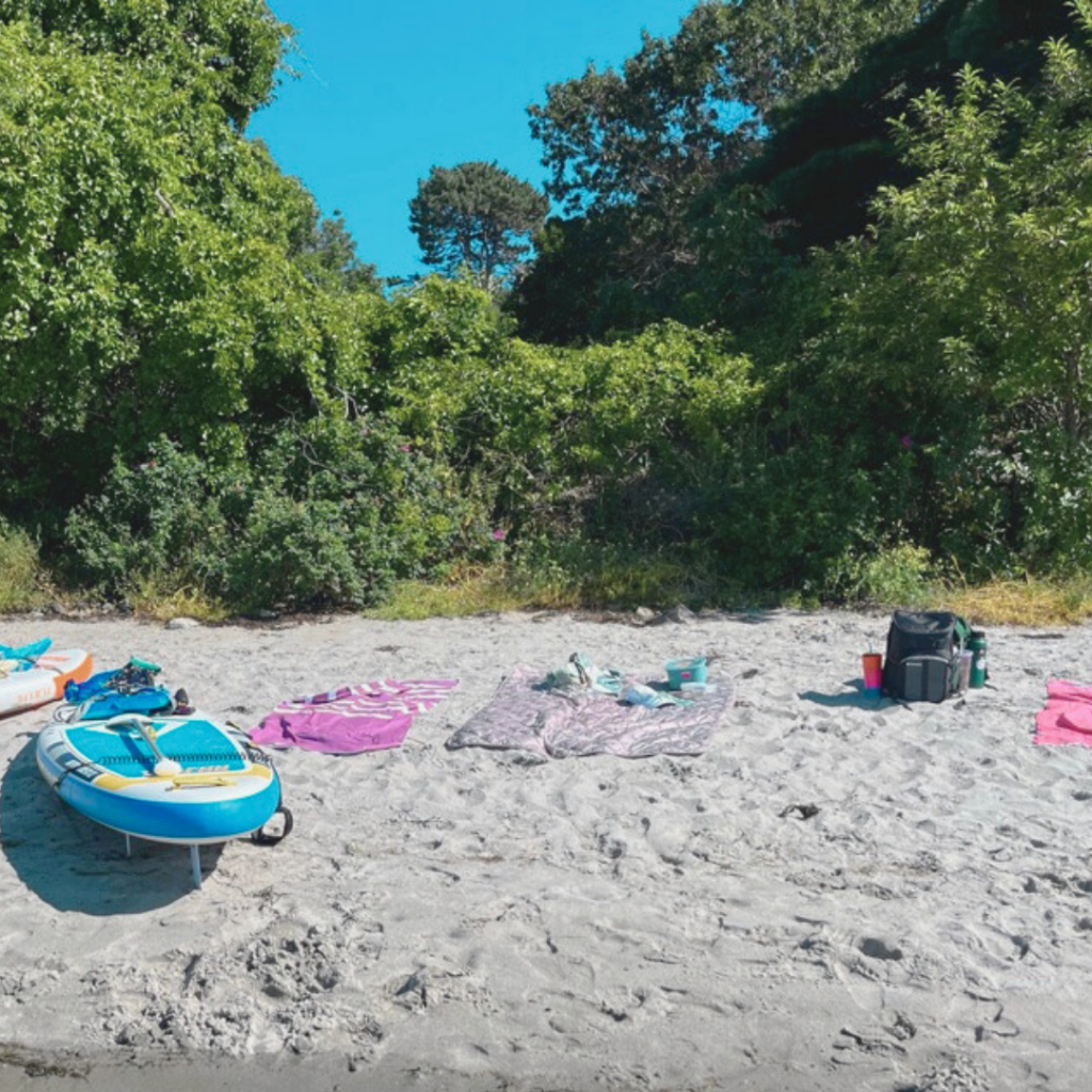 beach with a paddleboard, towels and a picnic